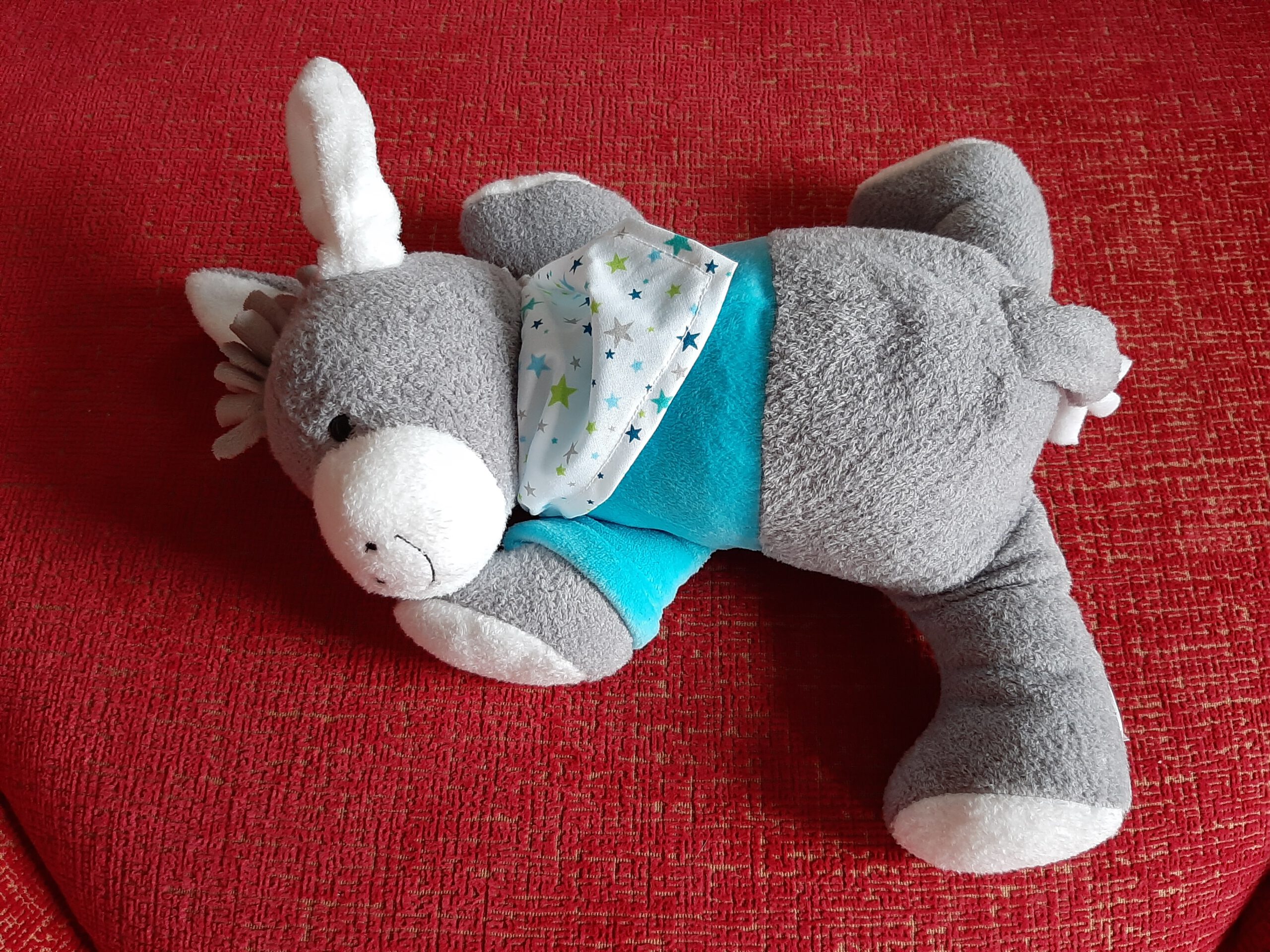 Ein grauer Stofftier-Esel mit einem Herzfrequenz-Sensor, der im Krankenhaus Trost spendete und nun als Erinnerung im Kindergrab meines Sternenkindes liegt.