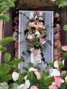 Grab von Arthur, einem Sternenkind, auf dem Friedhof in Pfaffenhofen an der Ilm. Der weiße Sarg ist mit Blumen, und rosa und weißen Blütenblättern geschmückt.